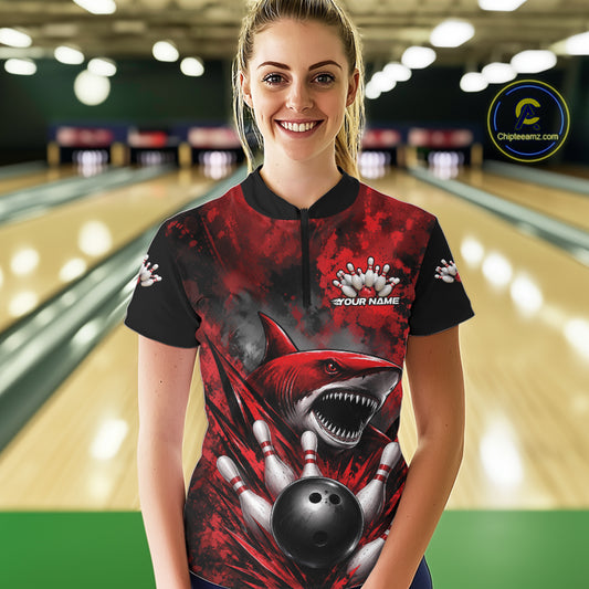 Woman wearing a red and black bowling shirt with a shark design in a bowling alley.