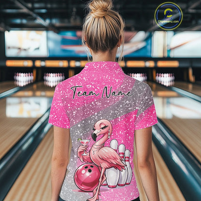 Back view of a female model in a bowling alley wearing a pink polo shirt featuring elegant flamingo artwork beside a bowling ball.