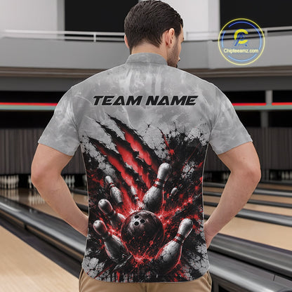 Front view of a male model wearing a gray bowling quarter zip shirt featuring a dramatic red bowling ball and pins graphic with claw-mark artwork at a bowling lane.