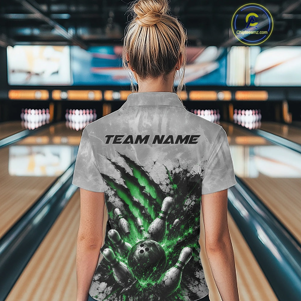 Back view of a female model wearing a gray bowling quarter zip shirt featuring a dramatic green bowling ball and pins graphic with claw-mark artwork in a bowling lane.