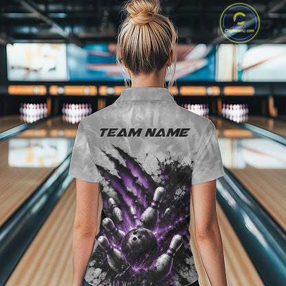 Back view of a female model wearing a gray bowling quarter zip shirt showcasing a dramatic purple bowling ball and pins graphic with claw-mark artwork in a bowling lane.