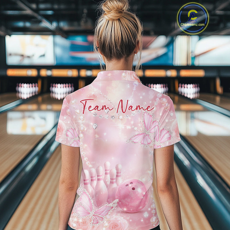 Back view of a female model at a bowling lane wearing a polo shirt featuring pink glitter butterflies, roses, bowling pins, and bowling ball artwork.