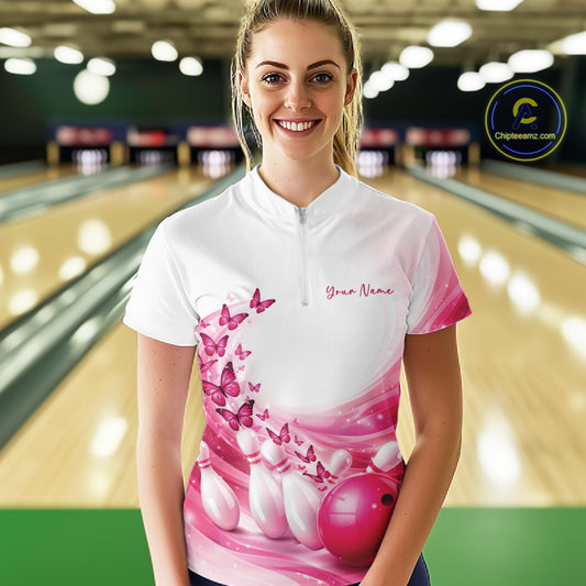 Front view of a female model wearing a white and pink bowling quarter zip with butterfly accents and bowling graphics at the bowling lane.