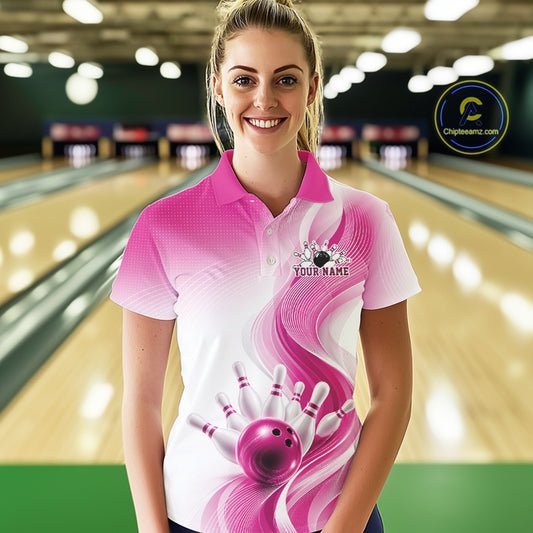 Front view of a female model wearing a white and pink bowling polo with flowing abstract wave accents and a glossy bowling ball striking pins