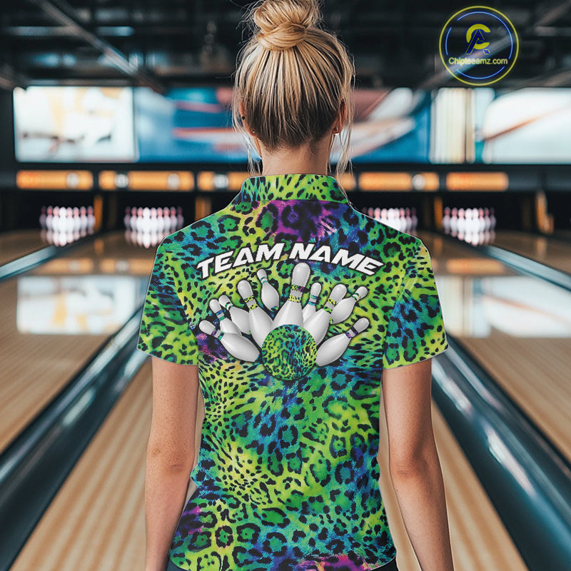 Back view of a woman standing at a bowling alley, wearing a gold, brown, and black leopard-print bowling polo with “Team Name” and bowling pins on the back.