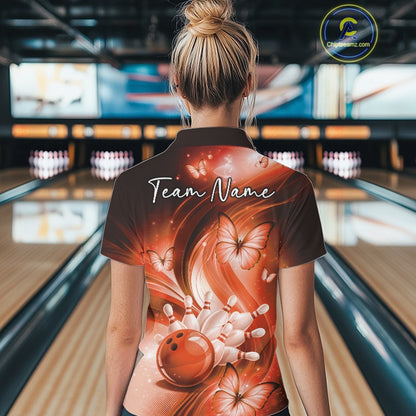 Back view of an orange womens bowling polo displaying a bowling ball, pins, and butterfly motif.