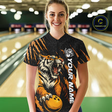 Load image into Gallery viewer, Front view of a female model at a bowling lane wearing a black and yellow bowling quarter-zip shirt featuring a roaring tiger holding a yellow bowling ball with orange claw-stripe graphics and a geometric background pattern.
