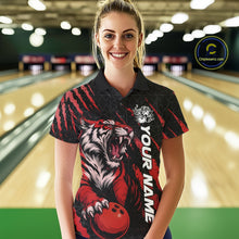 Load image into Gallery viewer, Front view of a female model at a bowling lane wearing a black and red bowling polo shirt showcasing a roaring tiger holding a red bowling ball with red claw-stripe graphics and a geometric background pattern.