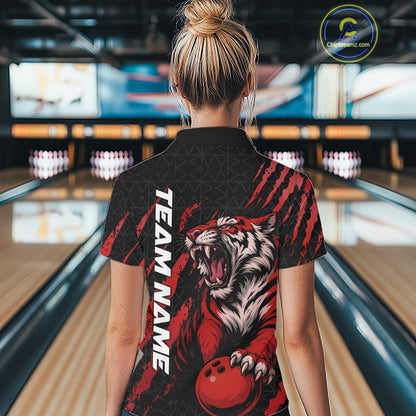 Back view of a female model wearing a black and red bowling quarter-zip shirt at a bowling lane, displaying a roaring tiger holding a red bowling ball with matching claw-stripe artwork and a geometric background pattern.