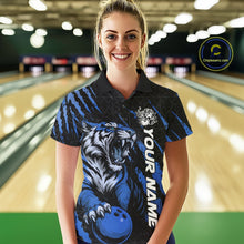 Load image into Gallery viewer, Front view of a female model at a bowling lane wearing a black and mid blue bowling polo shirt featuring a roaring tiger holding a mid blue bowling ball with coordinated claw-stripe graphics and a geometric background pattern.