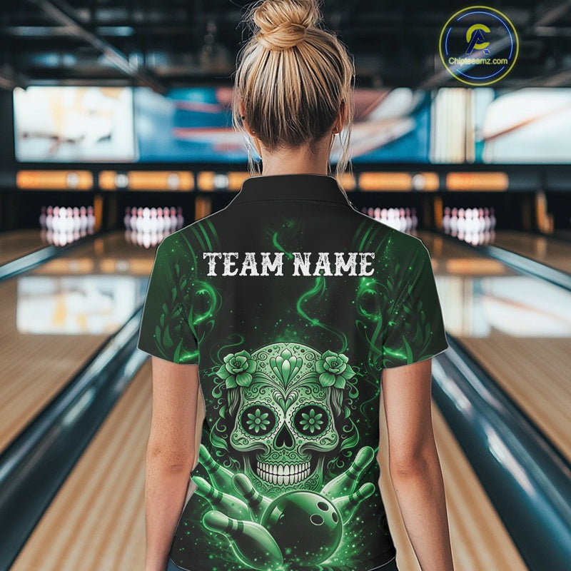 Back view of a female model in a bowling alley wearing a black and green polo with floral sugar skull and bowling ball graphics.