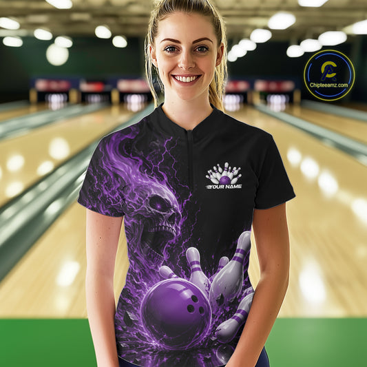 Front view of a female model in a bowling alley wearing a black quarter zip bowling shirt with a purple flaming skull, lightning, bowling pins, and a custom name.
