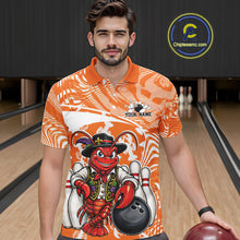 Load image into Gallery viewer, Front view of a male model in a bowling alley wearing an orange custom bowling polo shirt with a funny Cajun crawfish leaning on a bowling ball and a swamp inspired texture background.