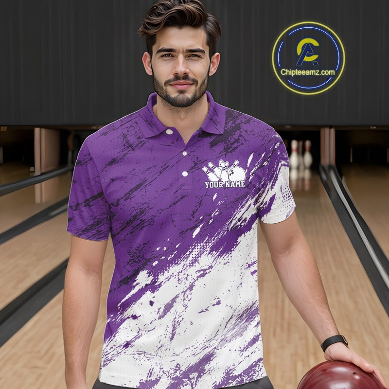 Front view of a male model in a bowling alley wearing a bowling polo shirt featuring a white and purple paint splatter distressed sportswear design.
