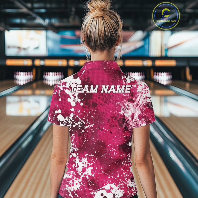 Person wearing a pink bowling shirt with 'TEAM NAME' printed on the back in a bowling alley.