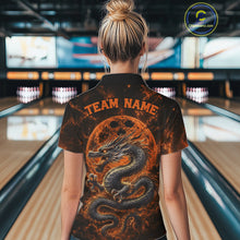 Load image into Gallery viewer, Back view of a female model in a bowling alley wearing an orange custom bowling polo shirt featuring an ancient dragon, flames, and a moon-inspired bowling ball design.