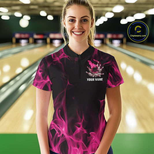 Female model wearing a black and pink bowling quarter-zip shirt at a bowling lane with bowling action graphics and fiery background accents.