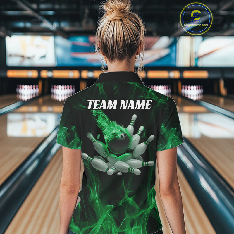 Back view of a female model in a bowling center wearing a black and green polo showcasing a bowling ball crashing through pins with flame effects.