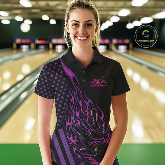 Female model at a bowling lane wearing a black bowling polo shirt with pink and purple flame bowling artwork and American flag accents.
