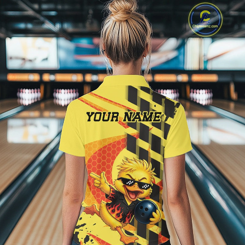 A woman viewed from behind wearing a bright yellow bowling-themed polo shirt with a cartoon bird graphic and 'YOUR NAME' printed on the back, standing in a bowling alley.