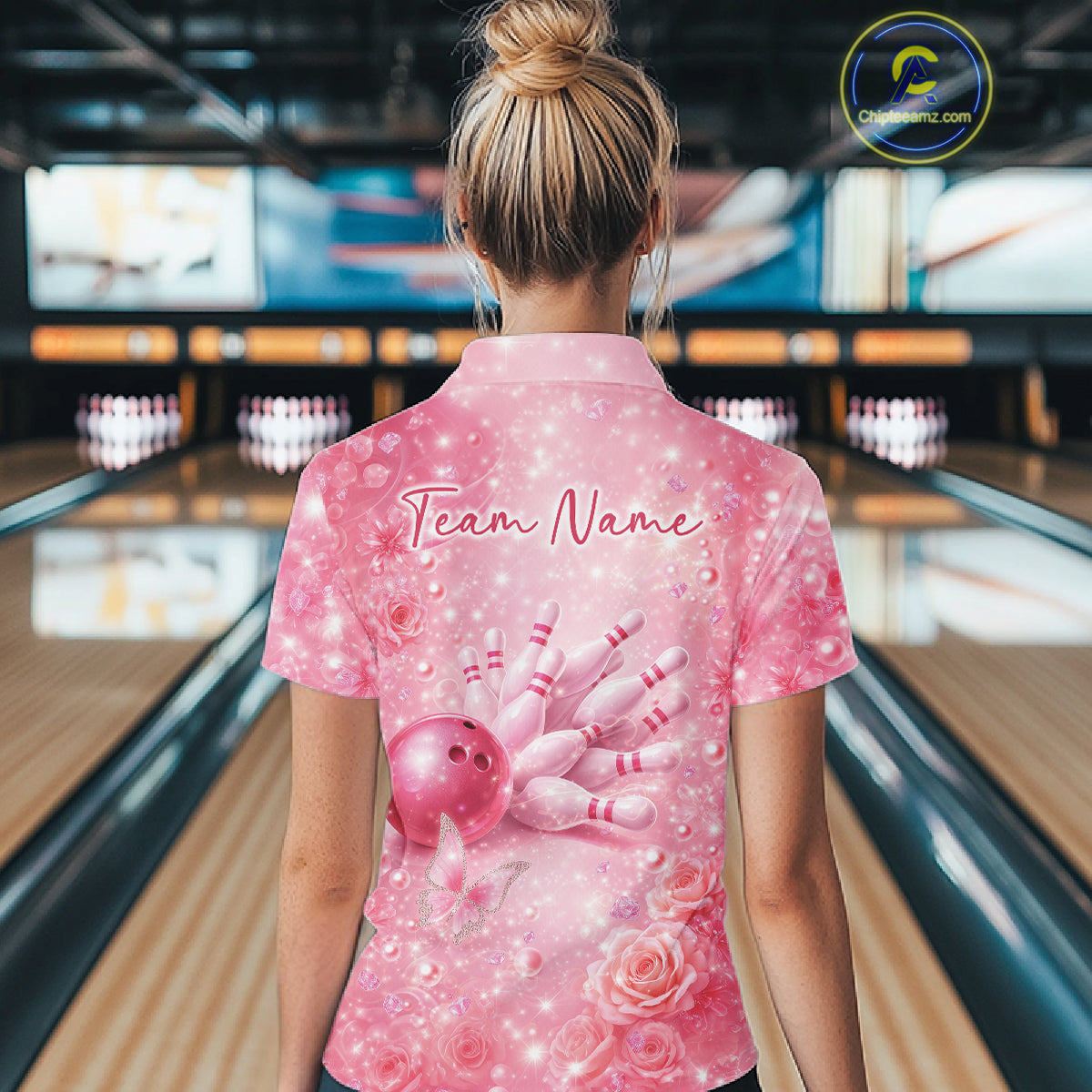 Back view of a female model wearing a pink quarter zip bowling shirt featuring a bowling ball striking pins with butterfly accents.