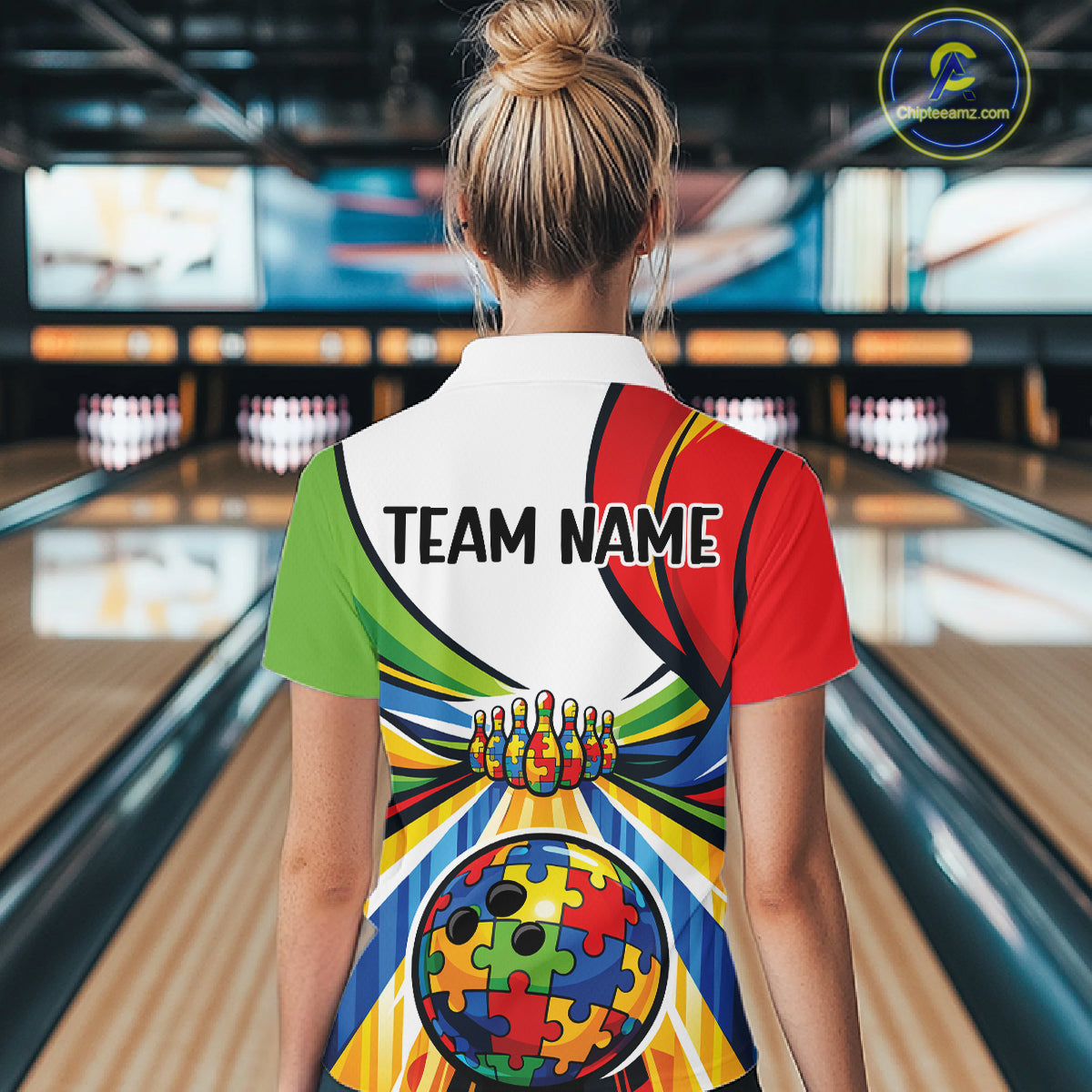 Back view of a female bowler wearing a quarter-zip shirt, autism-themed bowling lane artwork with multicolored puzzle elements.