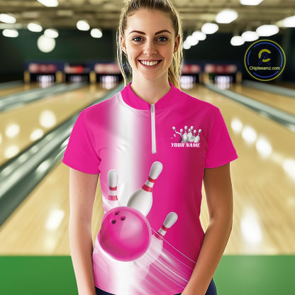 Front view female model at the bowling lane wearing a quarter zip shirt with bowling ball and pins flowing across a pink gradient design.