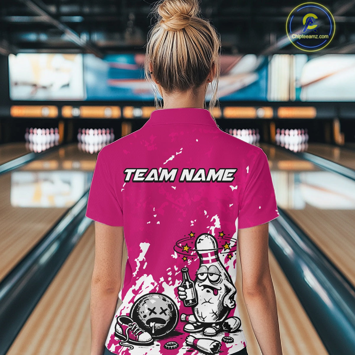 Back view female model wearing pink and white quarter zip bowling shirt in bowling lane, humorous bowling pin holding beer bottle design