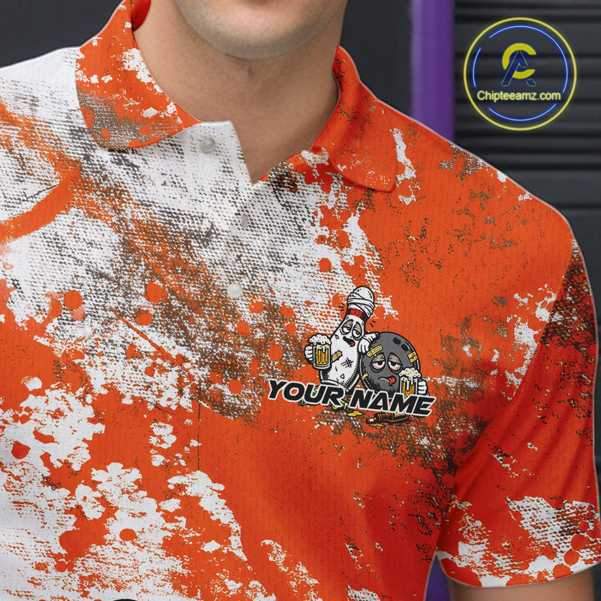Close-up view of the left chest of an orange and white grunge splatter polo shirt showing cartoon bowling pins and beer bottle detail artwork.
