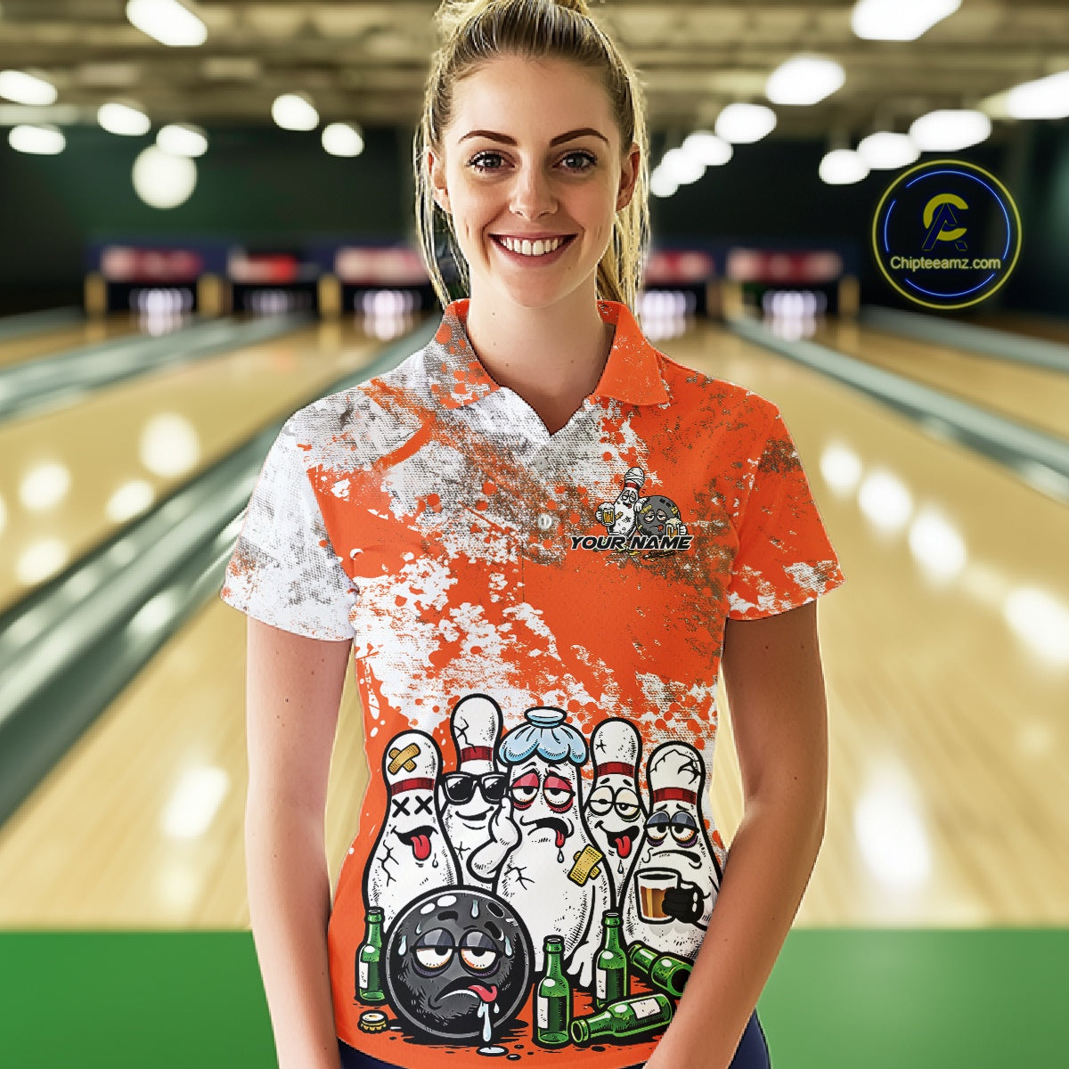 Female model front view at bowling lane wearing white polo with orange and white splatter pattern, cartoon bowling pins and bowling ball surrounded by beer bottles