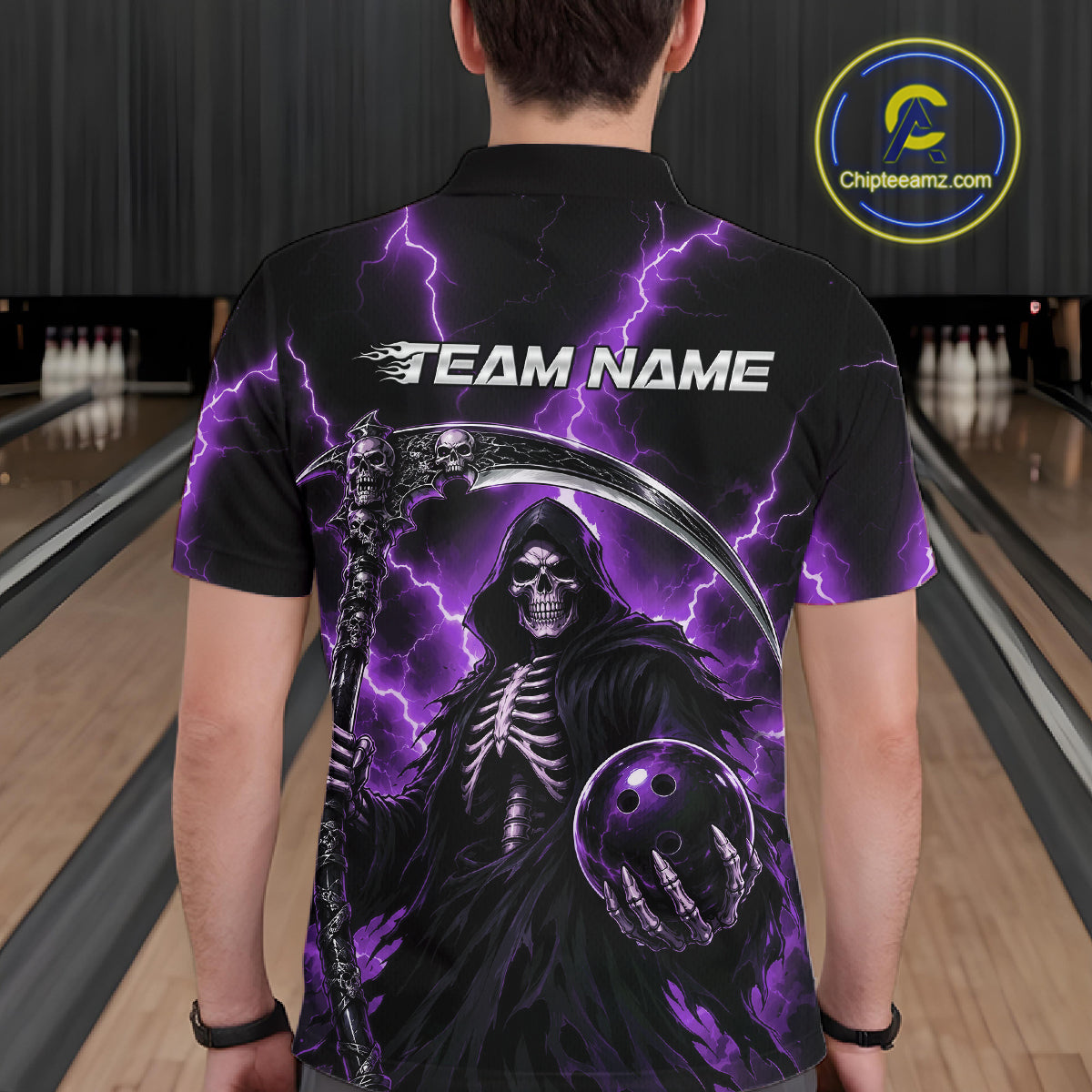 A person standing in a bowling alley wearing a black short-sleeve polo shirt with a large grim reaper graphic, purple lightning, and the text 'TEAM NAME' on the back. 
