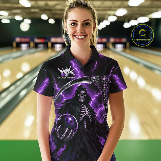 A woman wearing a custom black short-sleeve polo shirt with a purple and black grim reaper graphic, standing in a bowling alley. The shirt features a skeleton holding a bowling ball with purple lightning effects
