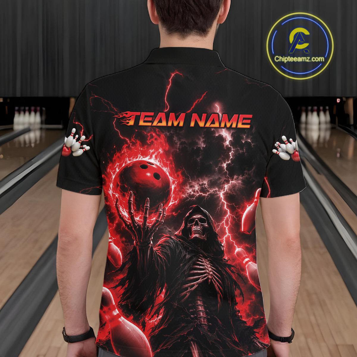 A person viewed from behind wearing a black short-sleeve collared shirt with a large red and black graphic print featuring lightning, a hooded figure, bowling balls, and the text 'TEAM NAME' across the upper back. Bowling lanes are visible in the background, and a circular 'Chipteamnz.