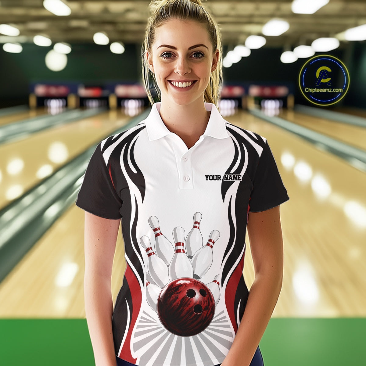 Front view of a female model inside a bowling center wearing a white, black, and red bowling polo shirt with bowling ball knocking down pins artwork.