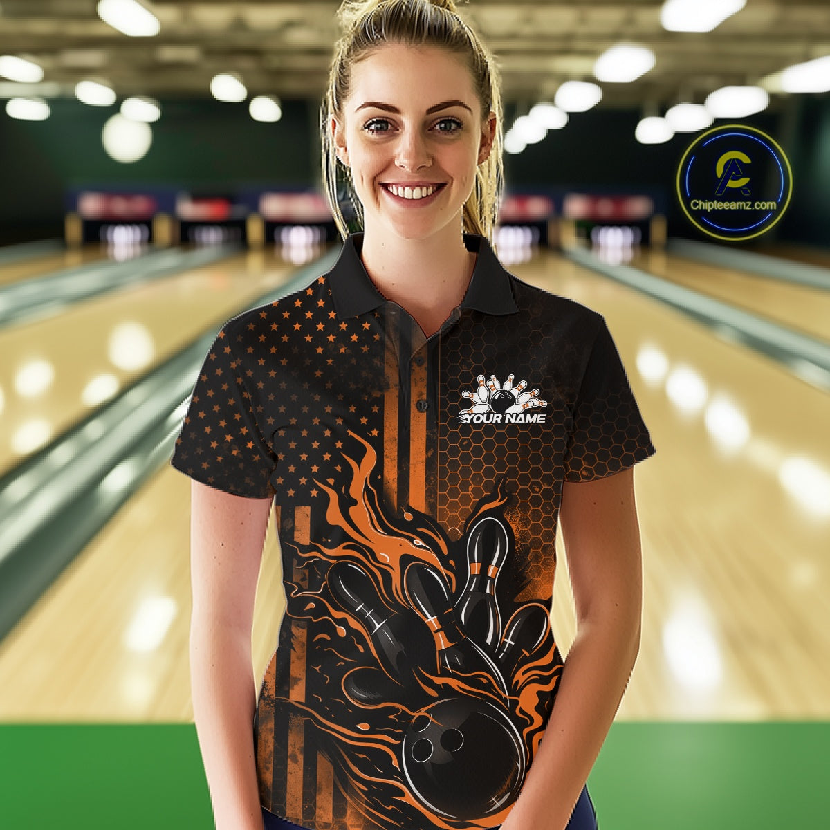 Female model at a bowling lane wearing a black and orange bowling polo shirt with fiery bowling strike artwork and patriotic details.