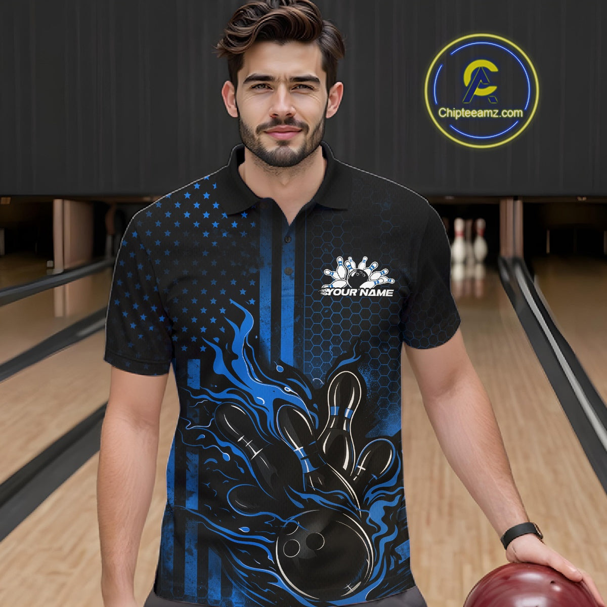 Male model at a bowling lane wearing a black and blue polo shirt with patriotic bowling strike artwork and fiery flag-inspired accents.