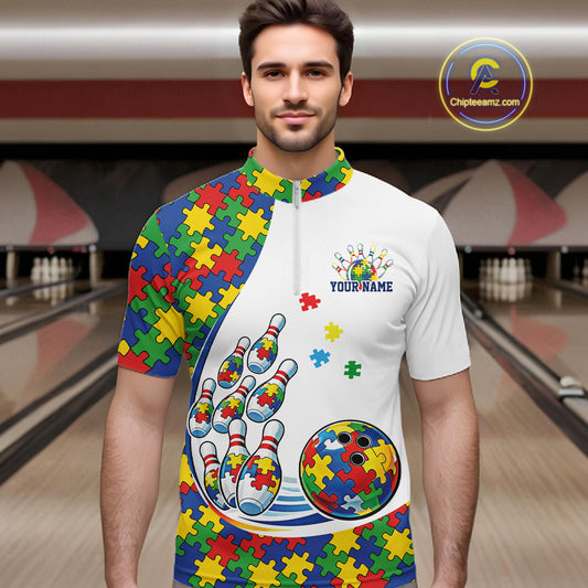 In A Bowling Lane, Front View Male Model Wearing White Quarter-Zip Shirt With Colorful Autism Bowling Strike Illustration And Puzzle Motif Graphics