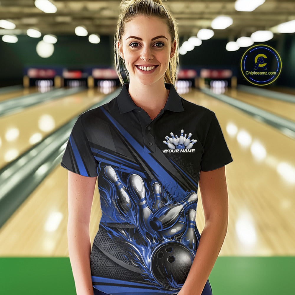 Female model in a bowling lane, front view wearing black polo shirt with blue flame bowling ball knocking down pins and abstract stripes