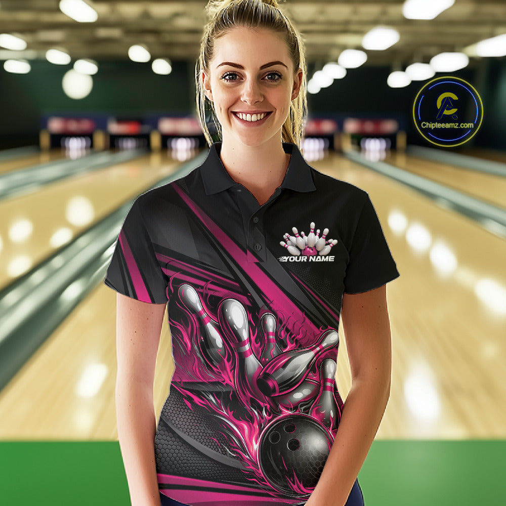 Female model at a bowling lane, front view wearing a black polo shirt with hot pink flame bowling ball knocking down pins and geometric stripes