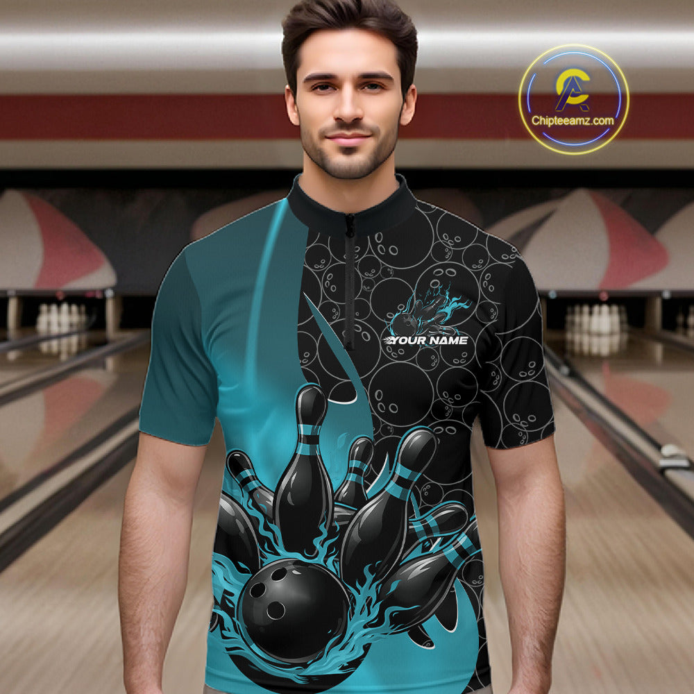 Male model front view at bowling lane wearing black and blue quarter zip shirt with fiery bowling ball graphic and pins impact scene