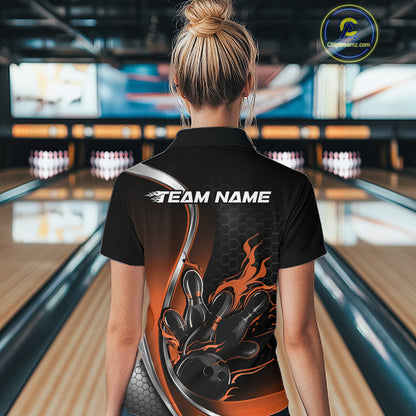 Female model back view at bowling venue wearing black and orange polo shirt showcasing flame bowling ball striking pins in bold motion artwork.