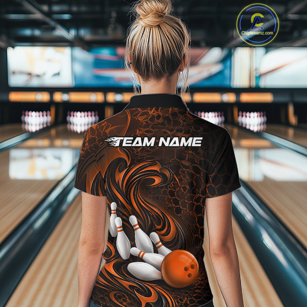 Female model standing in a bowling lane showing the back of a black and orange bowling polo shirt with a tribal flame bowling ball and pins graphic.