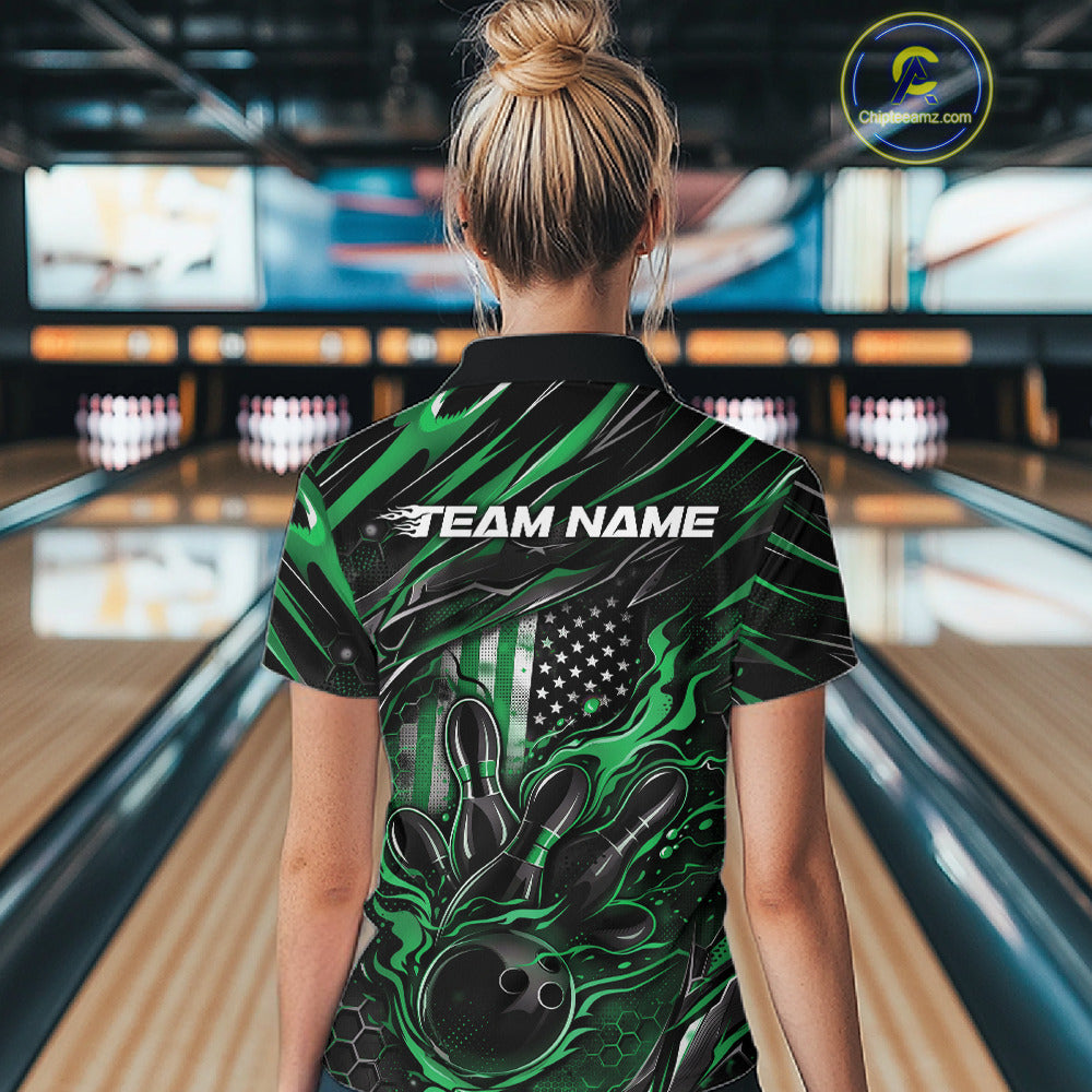 Back view of a female model in a bowling alley wearing a black and green polo shirt featuring a flaming bowling ball and patriotic pin artwork.