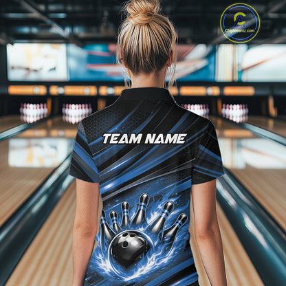 Back view of a female model in a bowling center wearing a black and blue polo shirt featuring a flaming bowling ball hitting the pins.