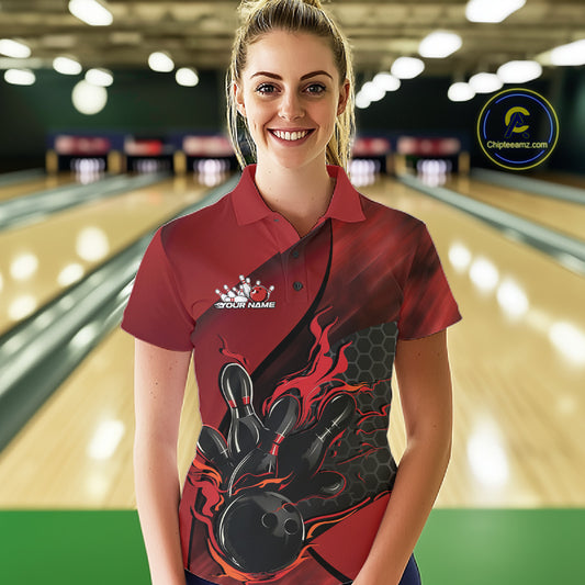 Female model wearing a black and red bowling polo shirt at a bowling lane with fiery bowling action artwork and geometric styling.