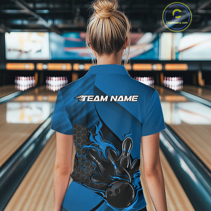 Back view of a female model in a bowling alley wearing a black and blue polo shirt featuring a flaming bowling ball knocking down pins.