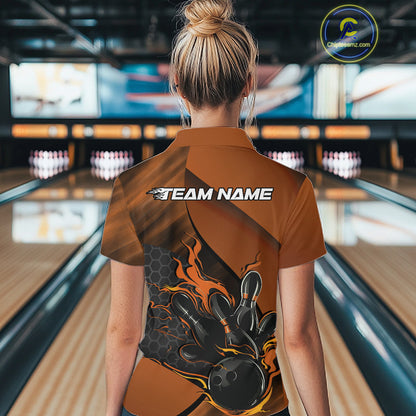 Back view of a female model in a bowling center wearing a black and orange polo shirt featuring a flaming bowling strike scene.