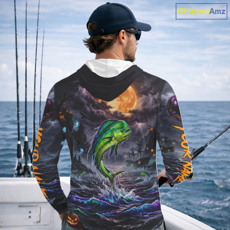A man on a boat wearing a long-sleeve hoodie with a detailed all-over graphic print. The design features a green mahi-mahi fish jumping from purple and blue ocean waves under a full moon, with fishing ships and lightning in the background.