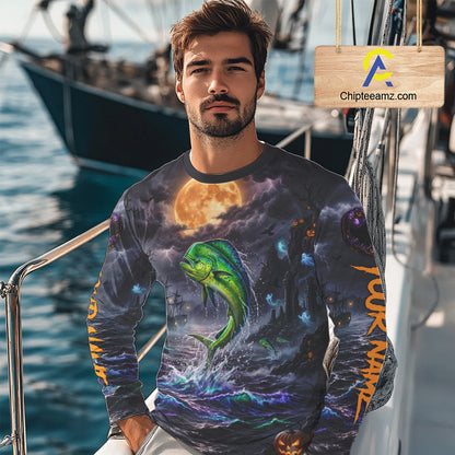 A man wearing a long-sleeve crewneck shirt with an all-over graphic print of a green dolphin jumping out of purple ocean waves under a large orange full moon, photographed on a boat deck with a visible Chipleamz.com watermark sign.