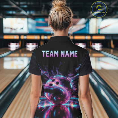Person wearing a black bowling shirt with a colorful bowling ball design and 'TEAM NAME' text in a bowling alley.